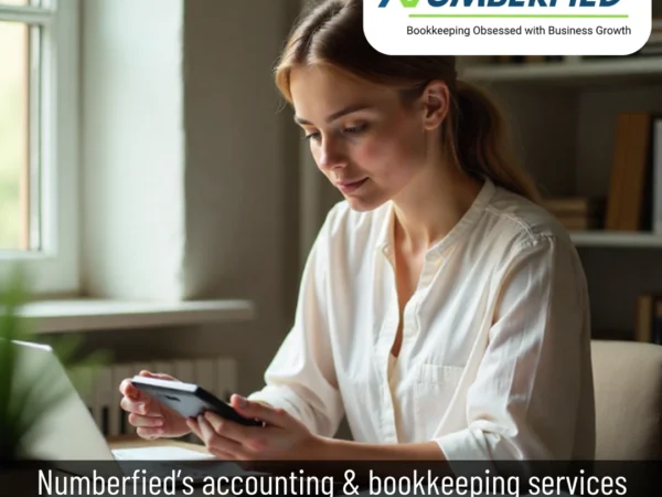 Young woman seated at a desk, focused on paperwork and a laptop, representing Accounting and Bookkeeping Services in a modern office setting.