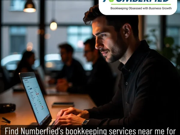 Professional handling bookkeeping tasks at desk as colleagues collaborate, showing bookkeeping services near me for small business.