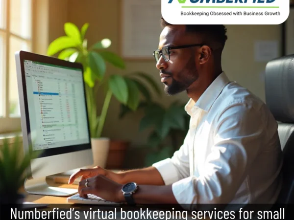 Professional providing virtual bookkeeping services for small businesses, sitting at a table and working on a laptop in a clean, well-lit office environment.